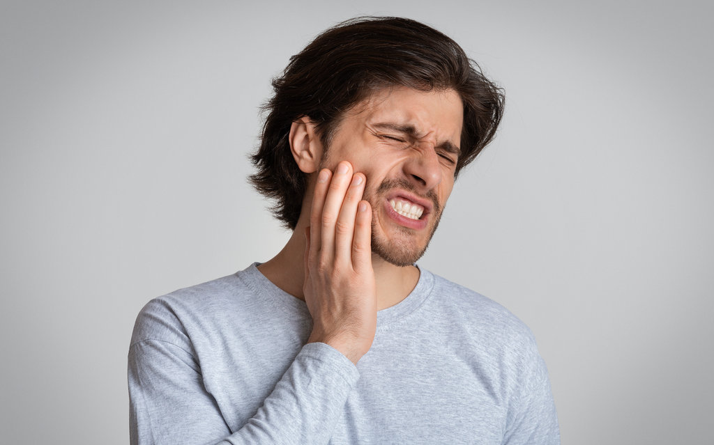 Young man suffering from terrible strong teeth pain
