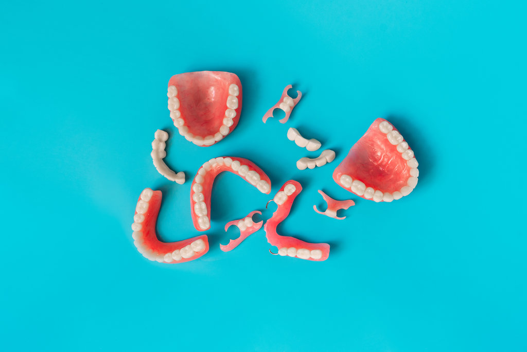 Dental prosthetics on a blue background. Dentures. Prosthetic teeth. False teeth. Prosthetic dentistry. Set of dentures on a blue background. Top view of complete denture on blue background
