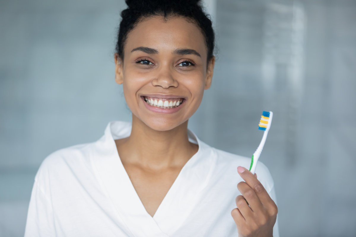 Portrait of happy african American millennial girl hold toothbrush recommend brushing teeth for healthy white smile, positive biracial young woman take care or oral hygiene, dentistry concept