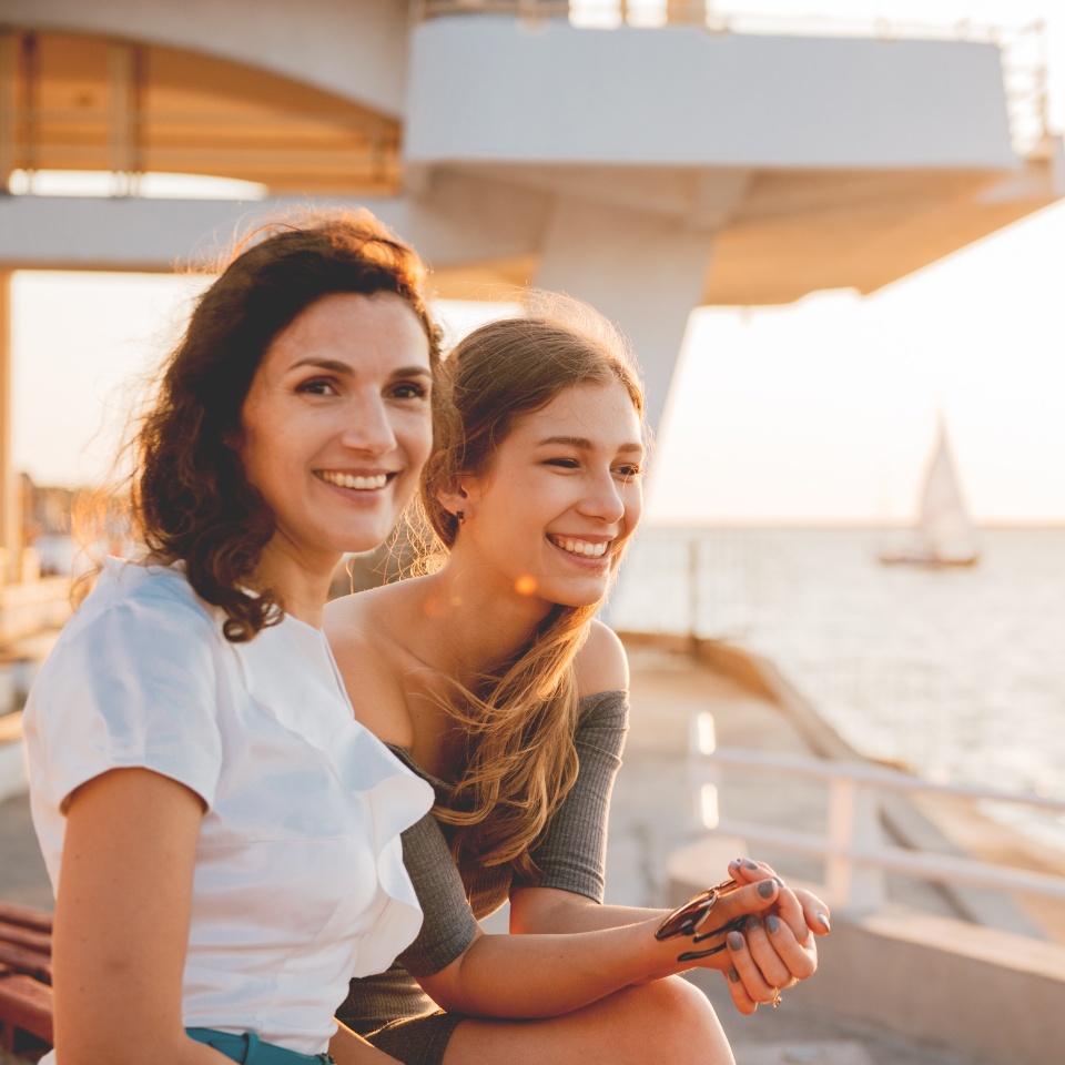 Close-up portrait of happy mother with teenage daughter. Sunset light.