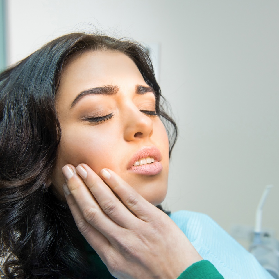 Young woman having toothache. Sad lady at the dentist. Gum disease symptom.