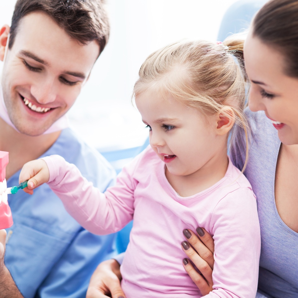 Dentist teaching girl how to brush teeth