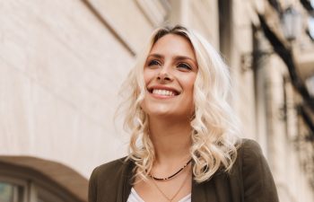 Image of caucasian woman wearing jacket using mobile phone for chat while walking through city street