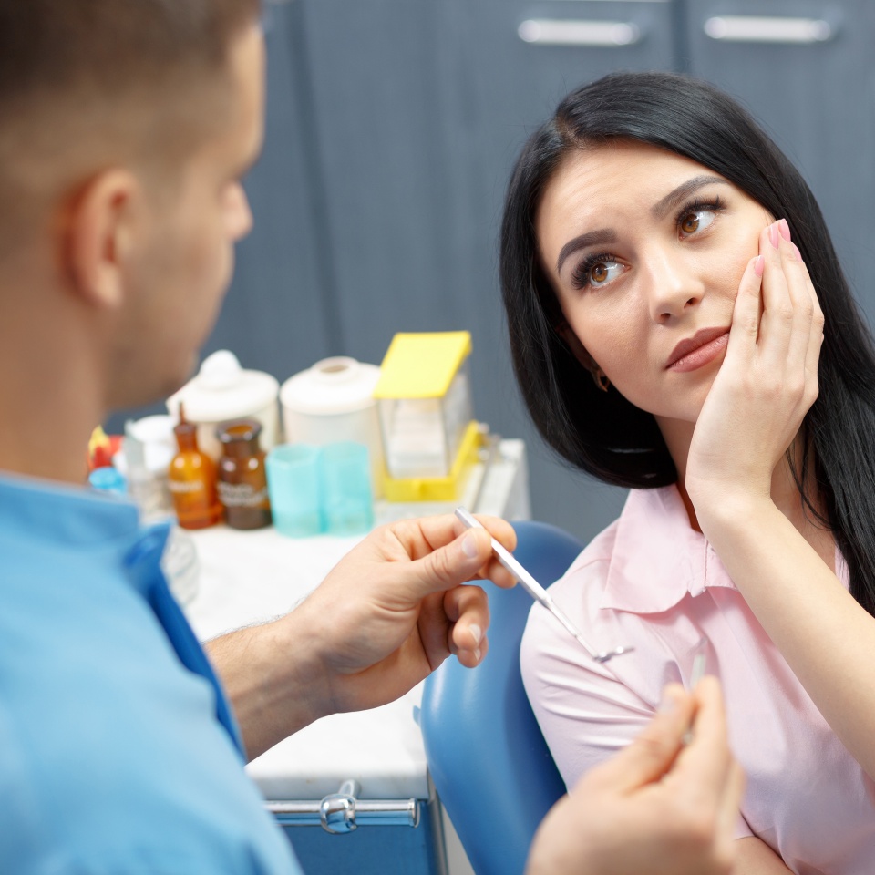 Girl patient goes to the dentist with a toothache in the dental office. Young woman holding the hand of a sick tooth