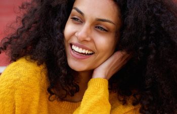 Close up portrait of young african lady with curly hair looking away and laughing