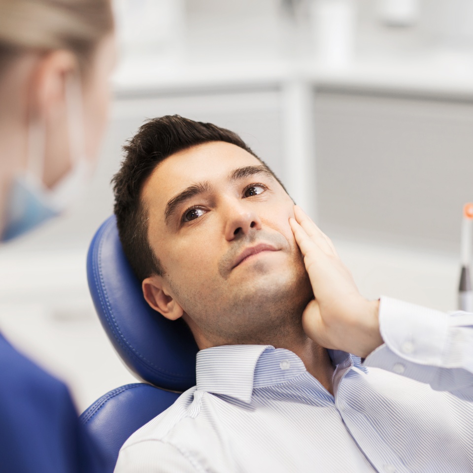 people, medicine, stomatology and health care concept - male patient with toothache complaining to female dentist at dental clinic office