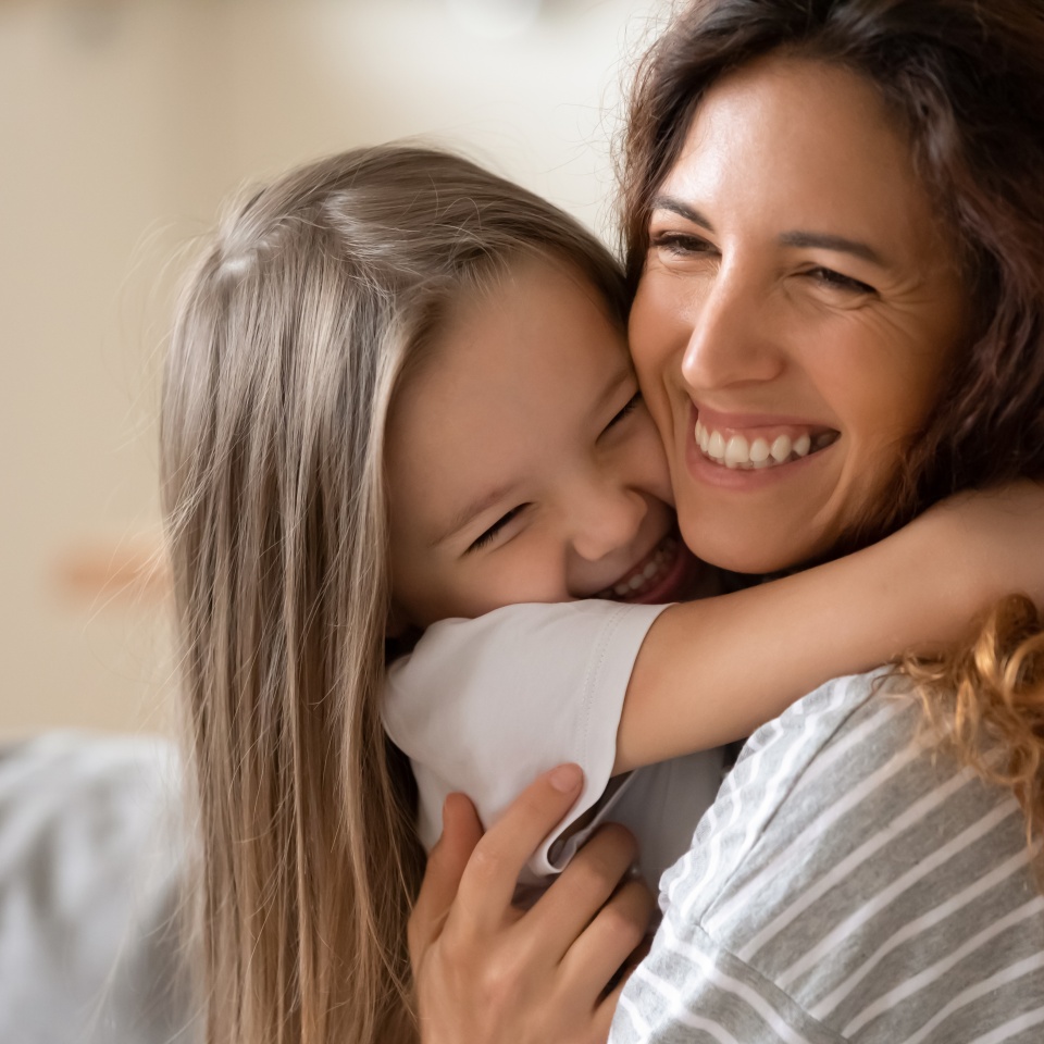 Cute little girl hug cuddle excited young mum show love and affection, smiling mother and funny small preschooler daughter have fun at home embrace sharing close tender moment together