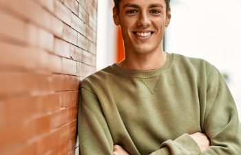 Young hispanic man smiling happy with arms crossed gesture at the city.