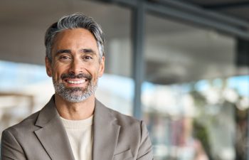 Happy middle aged business man entrepreneur looking at camera outdoors. Smiling confident mature businessman professional executive, successful lawyer wearing suit standing arms crossed, portrait.