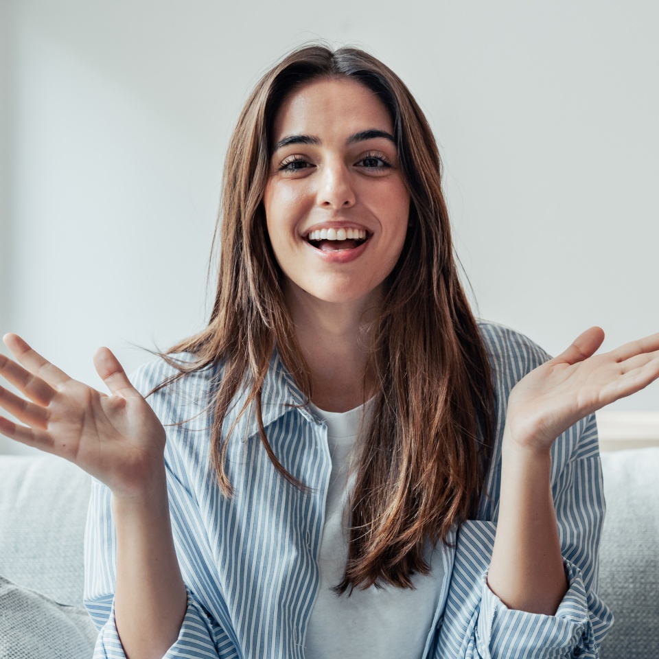 Head shot portrait smiling woman making video call to friends or relatives, using webcam, sitting on couch at home, happy young female blogger recording vlog, looking at camera, chatting online