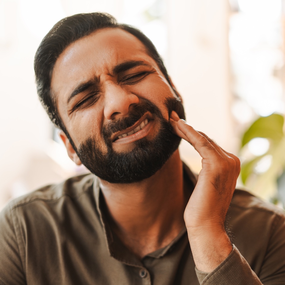 Portrait of sad middle aged Indian man touching face, toothache, closeup. Dental care concept, health care