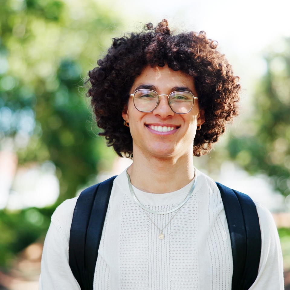 Man, student and smile for portrait at park, pride and excited on commute to university in spring. Person, happy and backpack on path for scholarship, learning or education at college in Costa Rica