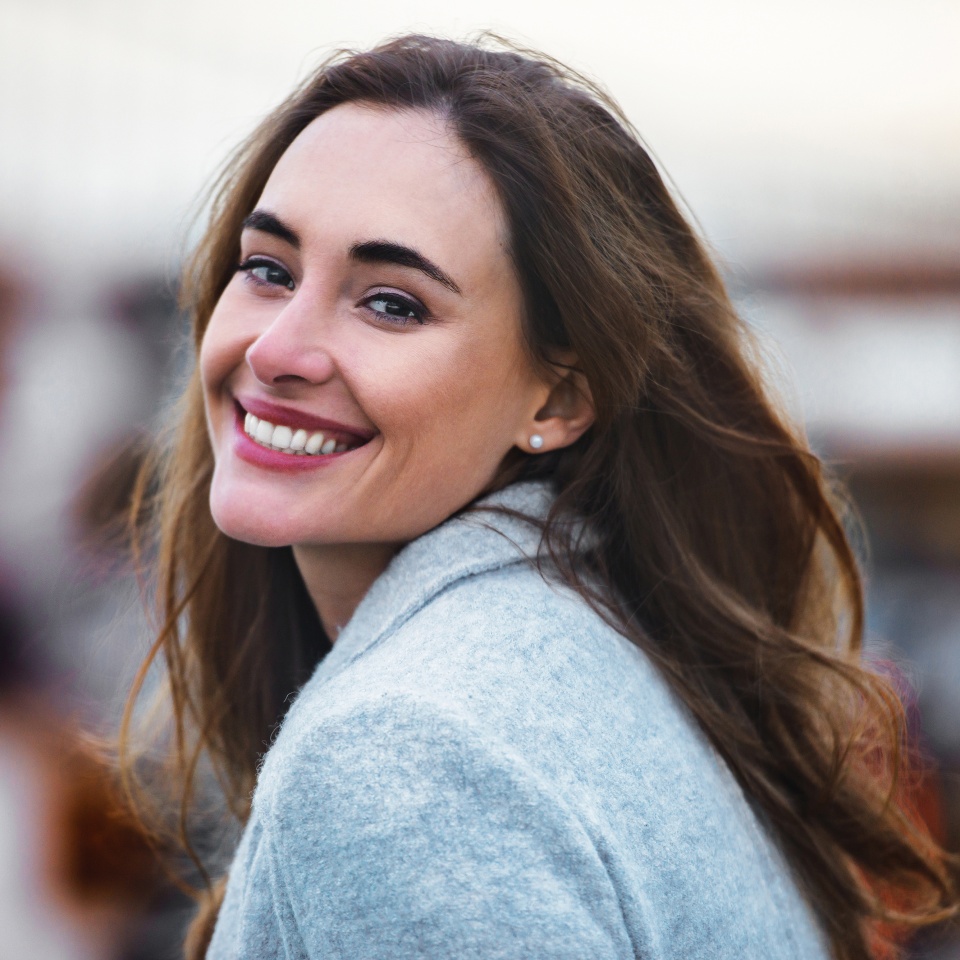 Close-up portrait of beautiful caucasian woman with charming smile walking outdoors