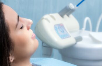 Close up side view portrait of young woman at dental check up.Girl laying with eyes closed with equipment in background.