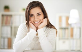 Happy girl in white pullover looking at camera with smile