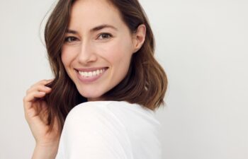 Portrait of beautiful naturally brunette woman, smiling and looking in camera with white teeth. Close-up portrait of cute female girl isolated on white background.